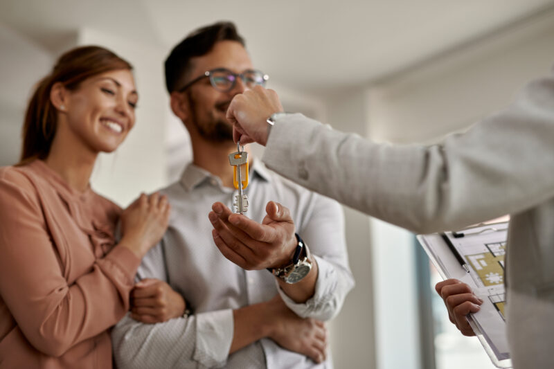 close up of real estate agent giving new house keys to a couple.